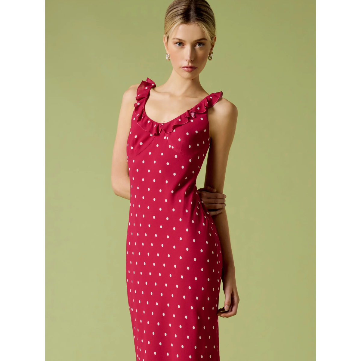 Woman wearing a red polka dot dress against a green background