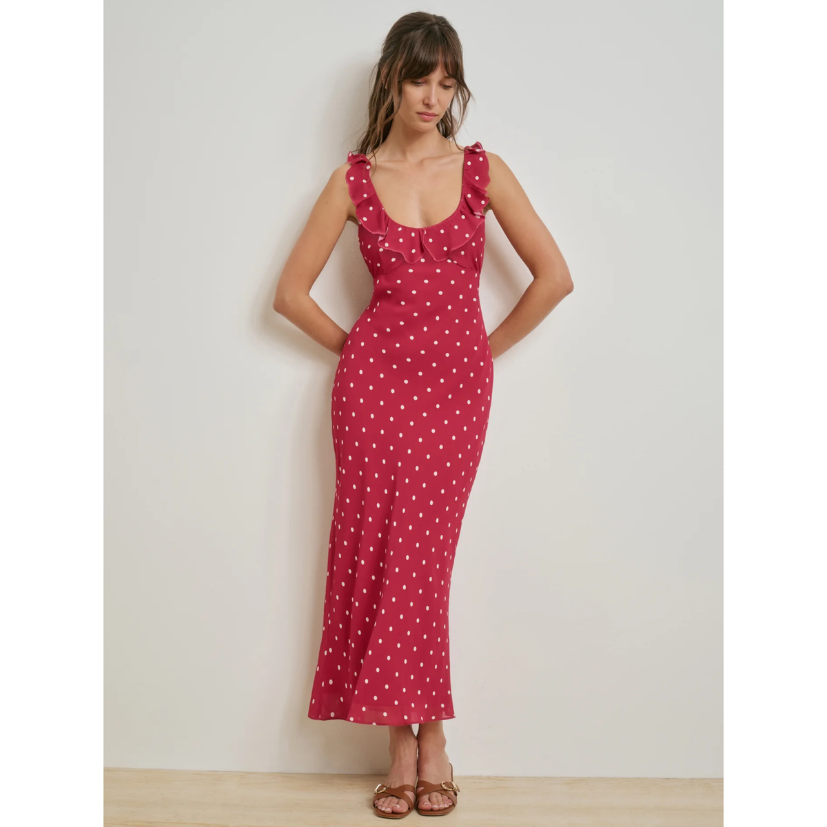 Woman wearing a red polka dot dress against a plain background