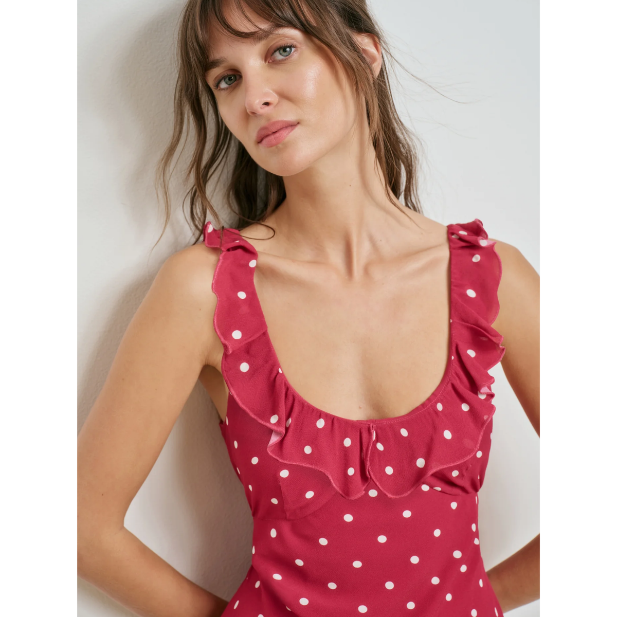 Woman wearing a pink polka dot dress against a white background