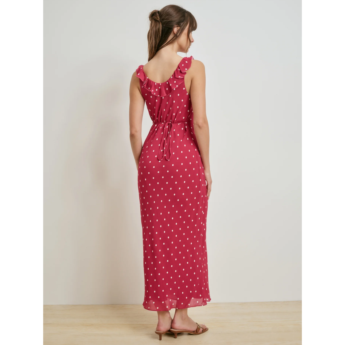 Woman wearing a red polka dot dress against a plain background