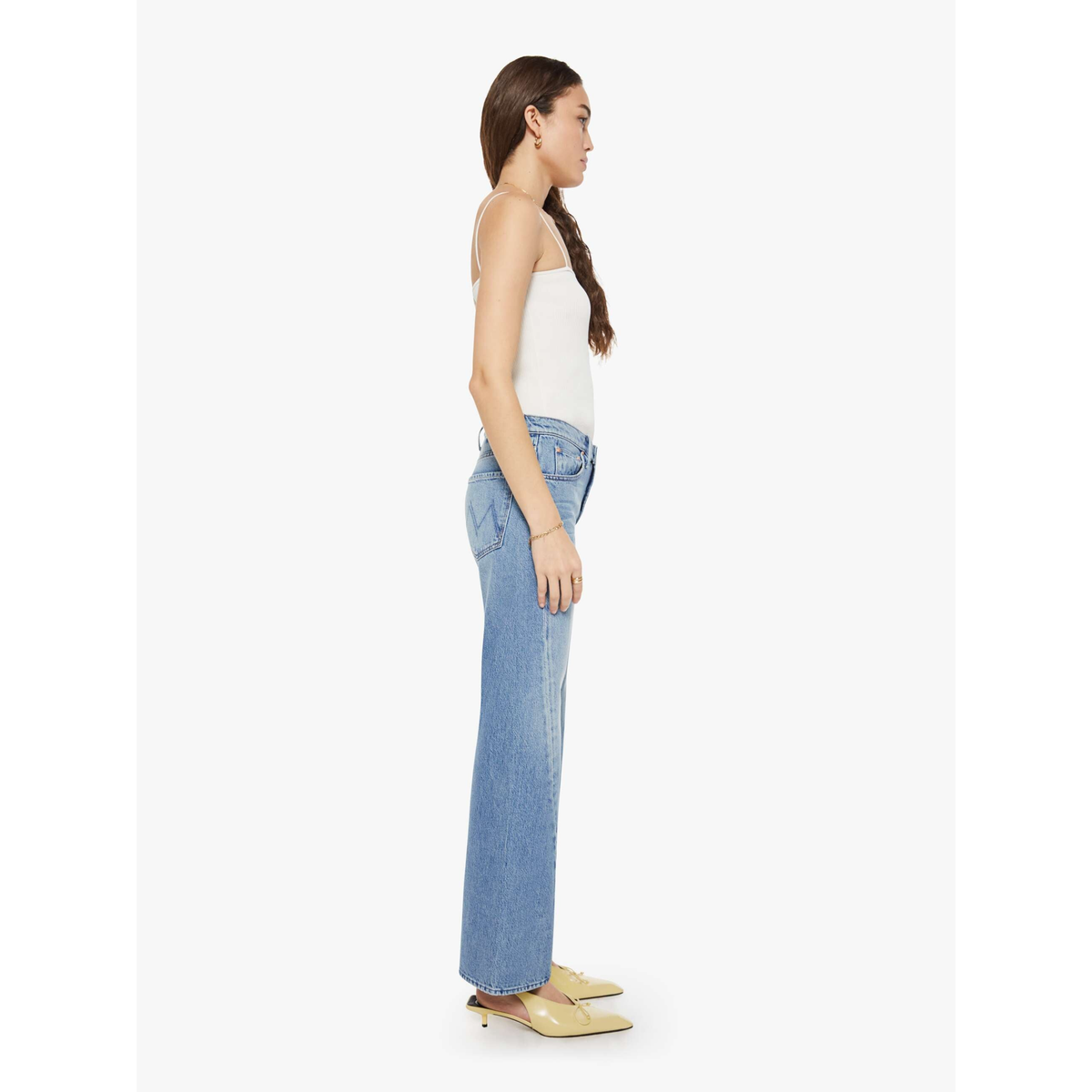 Woman wearing light blue jeans and a white top on a white background