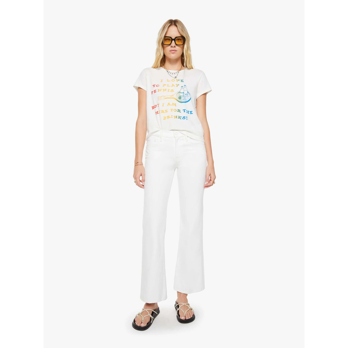 Woman wearing a white t-shirt with colorful text and graphics, paired with white pants on a white background.