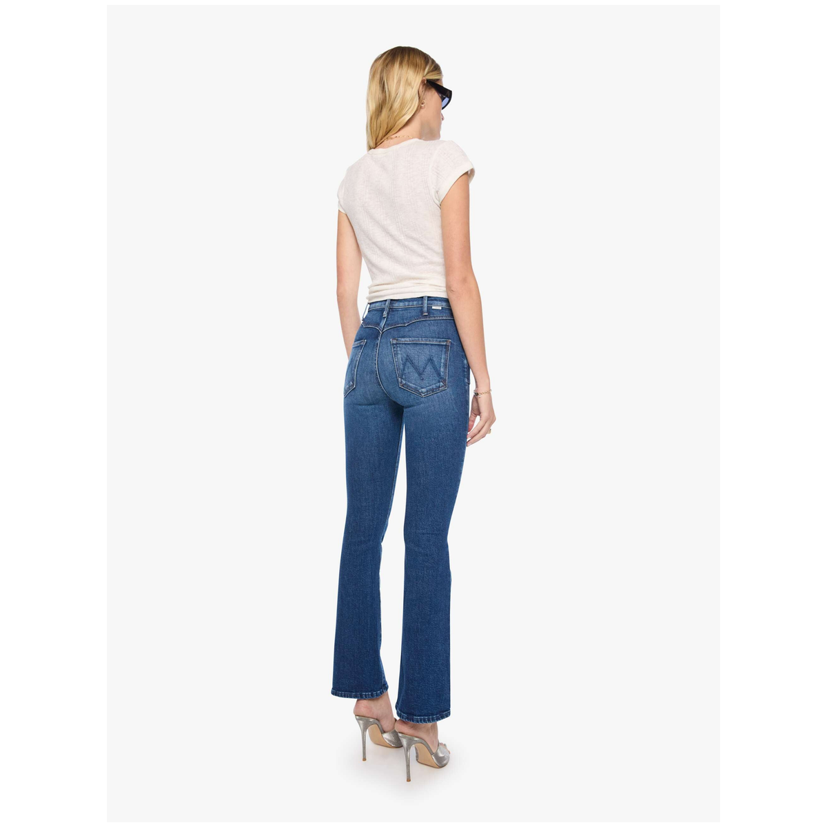 Woman wearing blue jeans and a white top on a white background