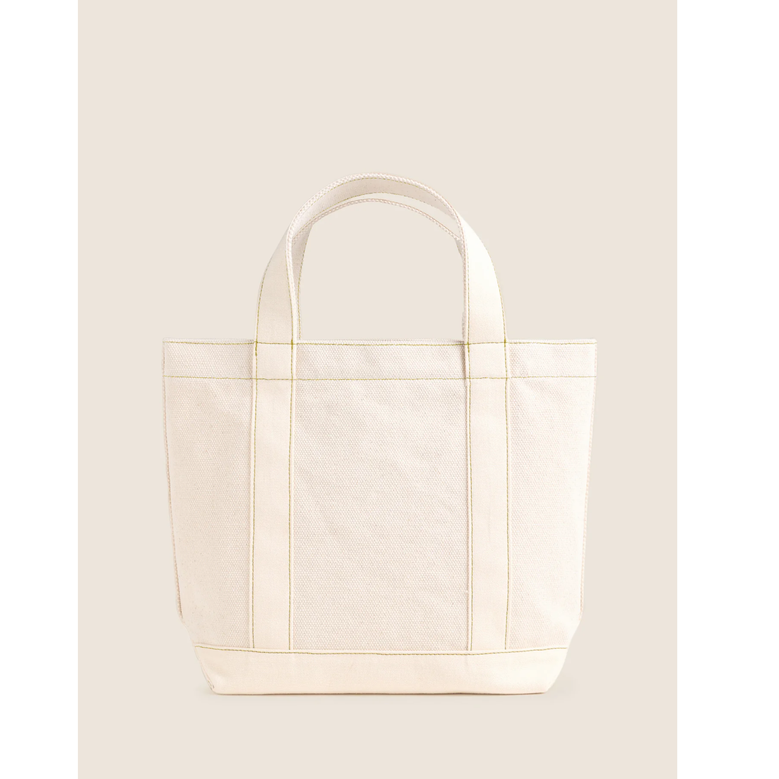 An off-white canvas tote bag with gold foil script reading 'femme daguer' and a small gold heart on the front, set against a solid light beige background.