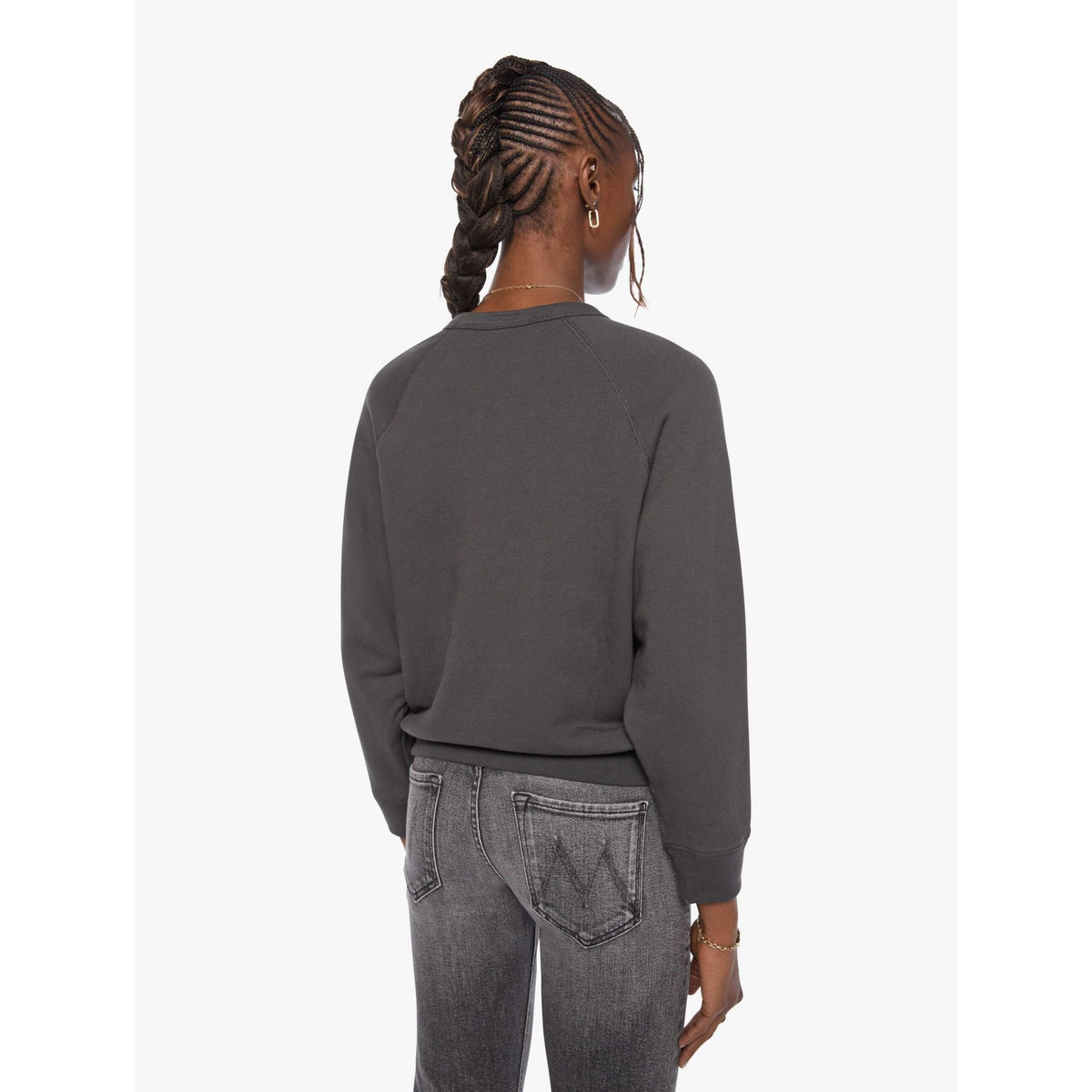 A woman shown from the back wearing a dark charcoal gray crewneck sweatshirt and gray jeans, photographed against a clean white studio background.