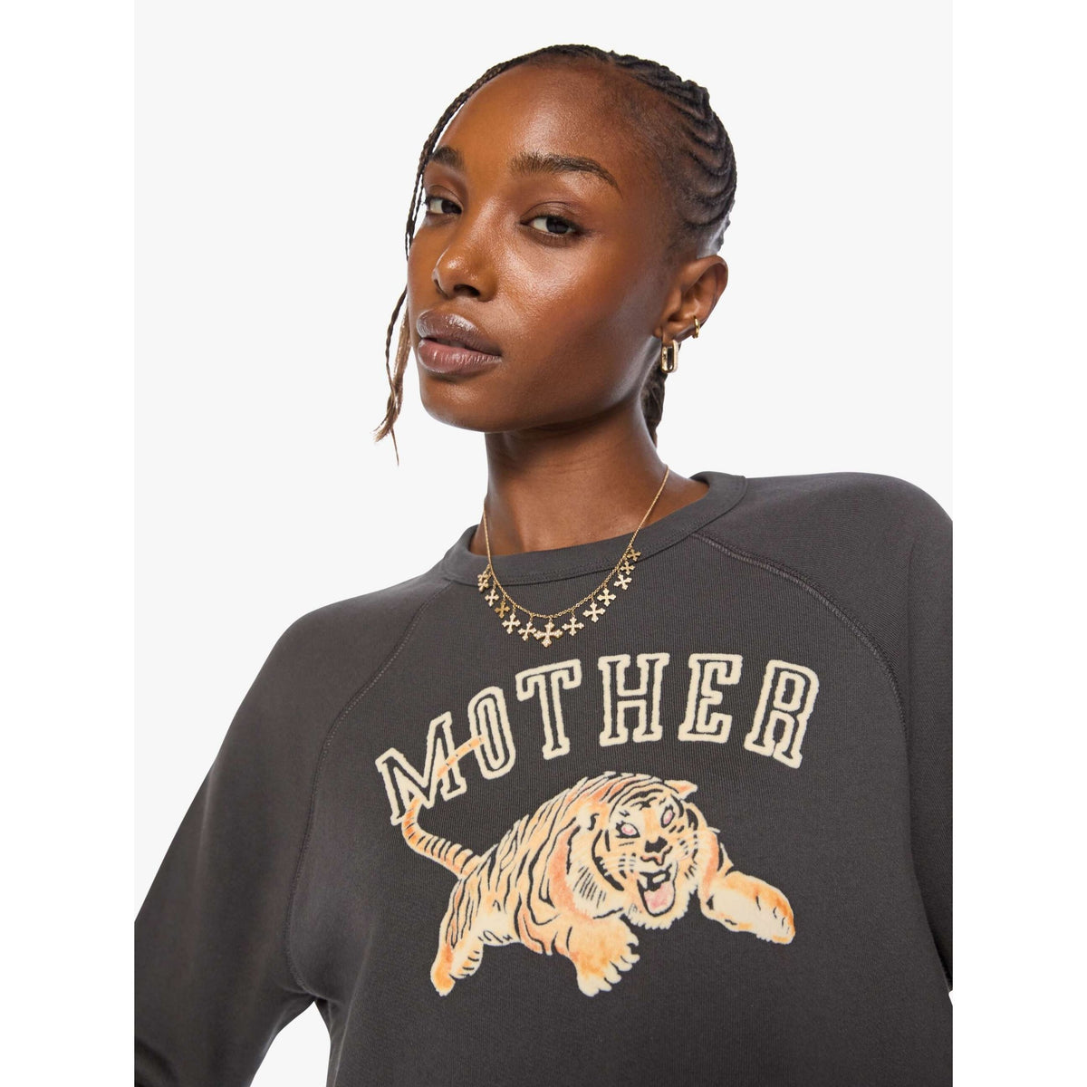 A woman wearing a dark charcoal gray sweatshirt with a graphic of a running tiger and the word 'MOTHER' in cream lettering, shown against a light gray background.