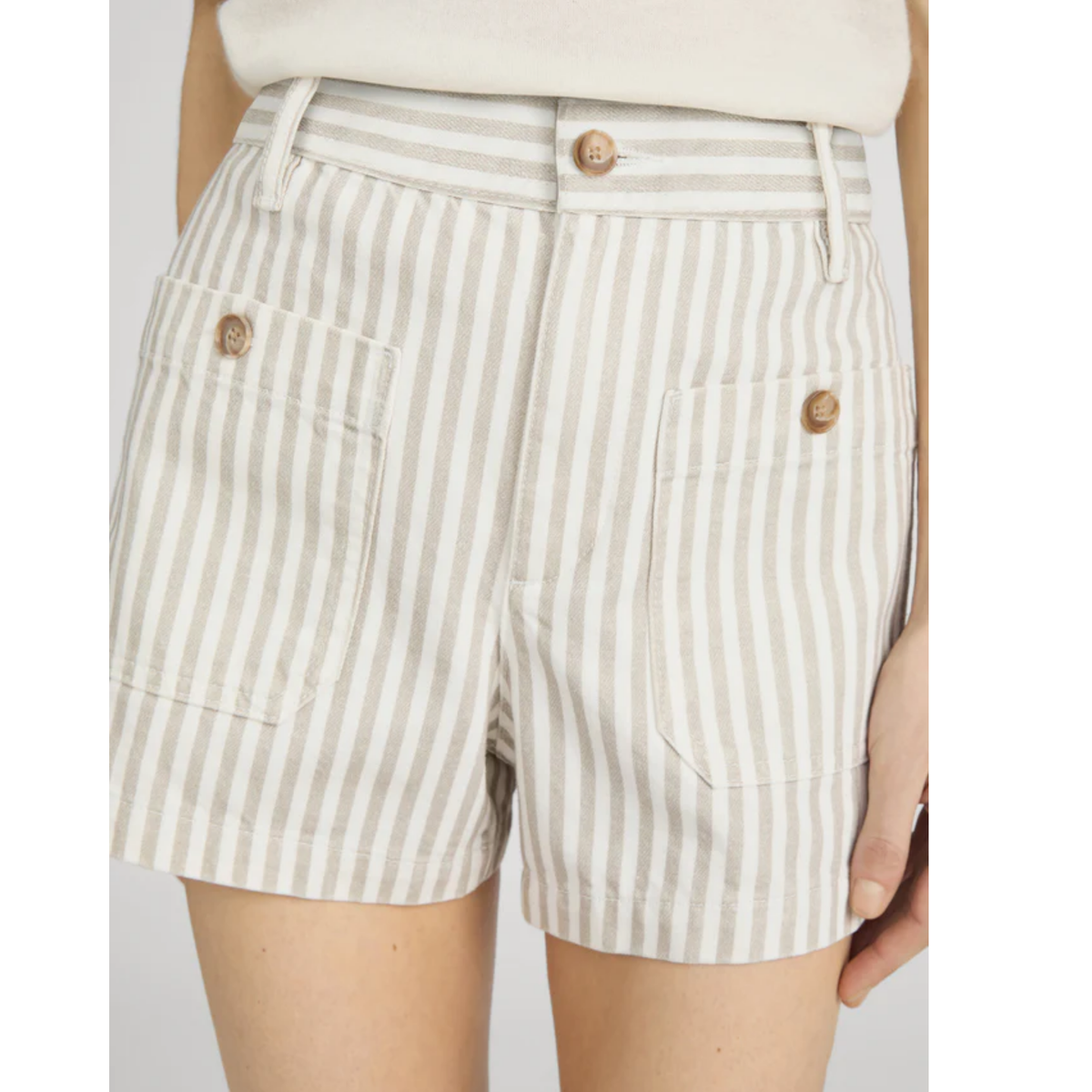 Beige and white striped shorts worn by a person on a plain background