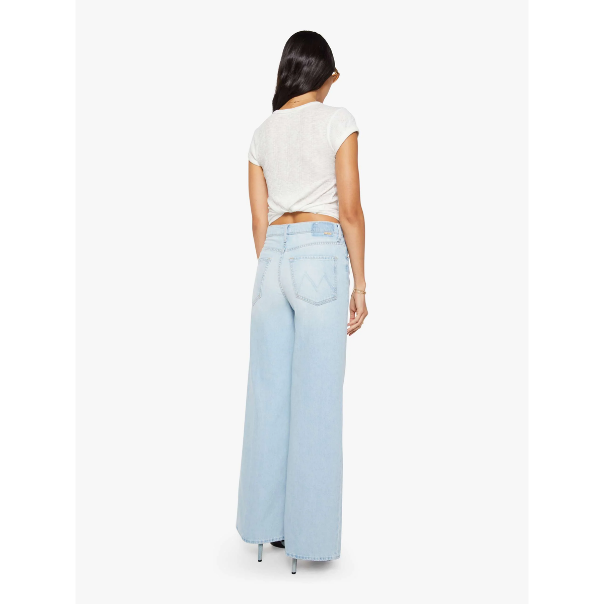Person wearing light blue jeans and a white top on a white background