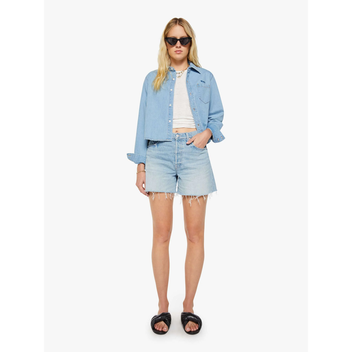 Woman wearing a light blue denim jacket and shorts on a white background
