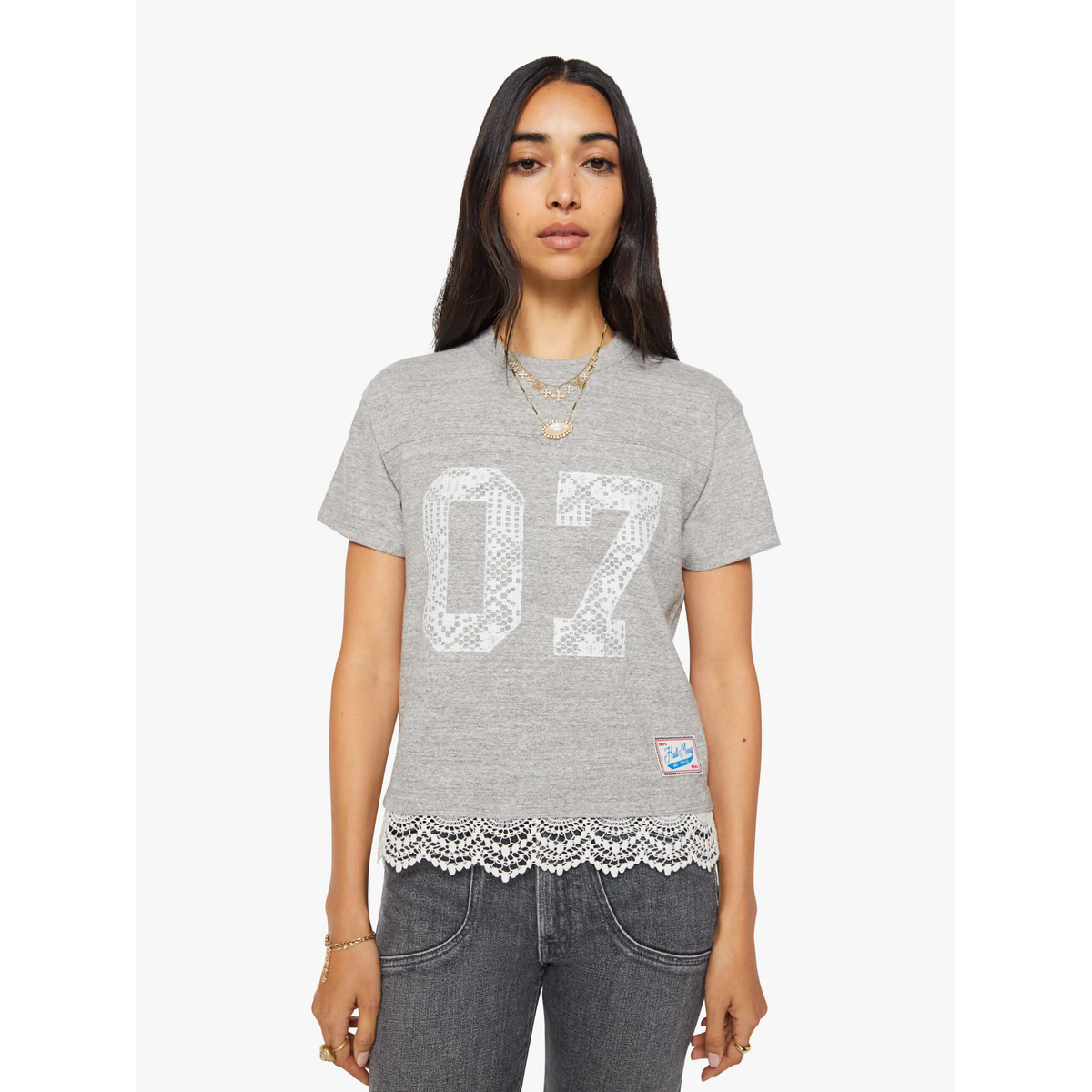 Woman wearing a gray t-shirt with lace hem and '07' print on a white background