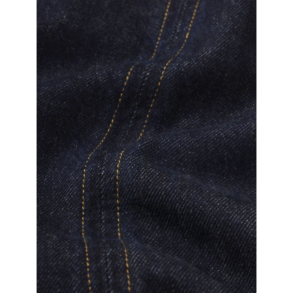 Close-up of dark indigo denim fabric with contrasting yellow-orange stitching.