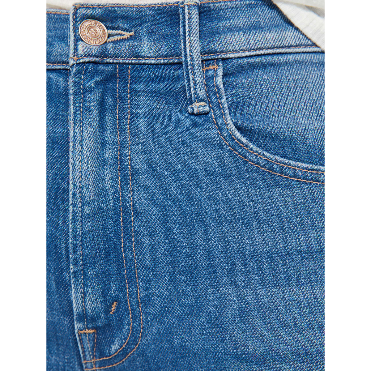 Close-up of blue denim jeans with stitching details on a white background