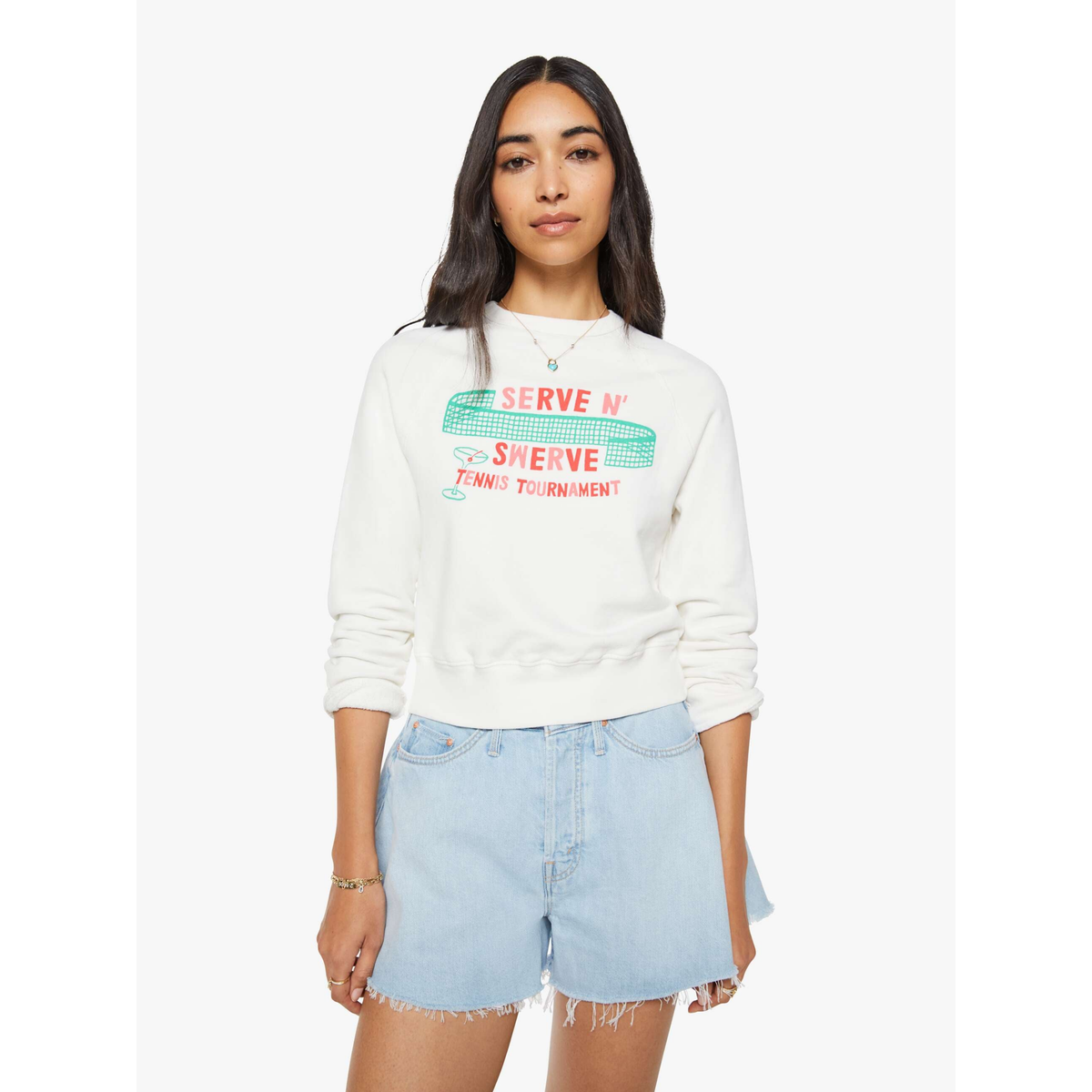 Woman wearing a white sweatshirt with colorful text and light blue denim shorts on a white background