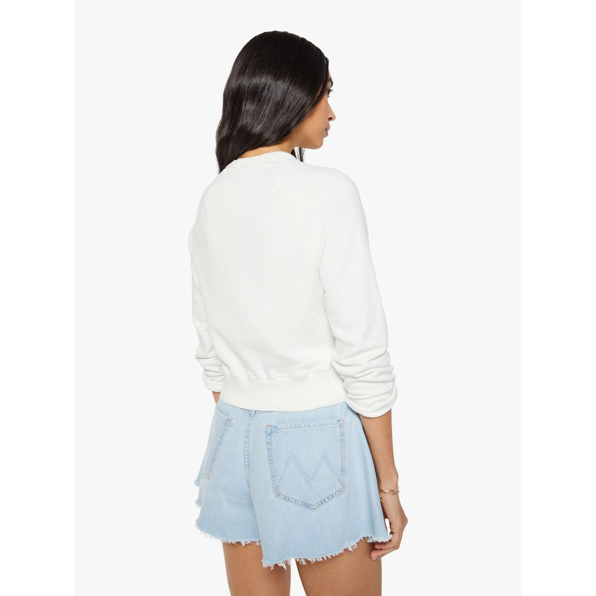 Woman wearing a white sweater and light blue denim shorts on a white background