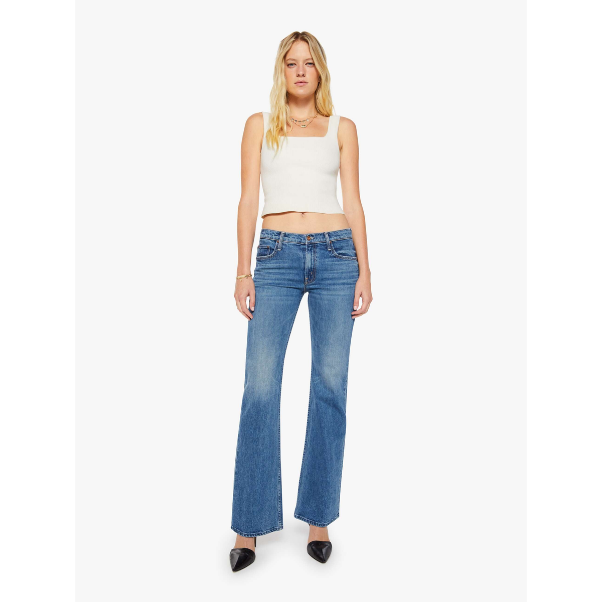 Woman wearing blue flared jeans and a white top on a white background