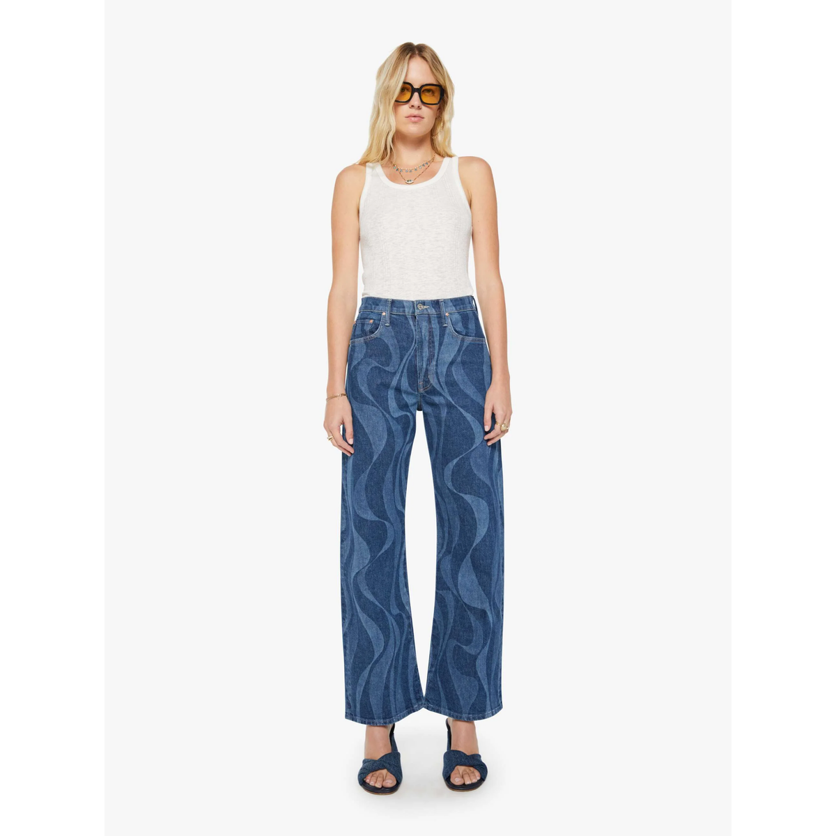 Woman wearing blue patterned jeans and a white top on a white background