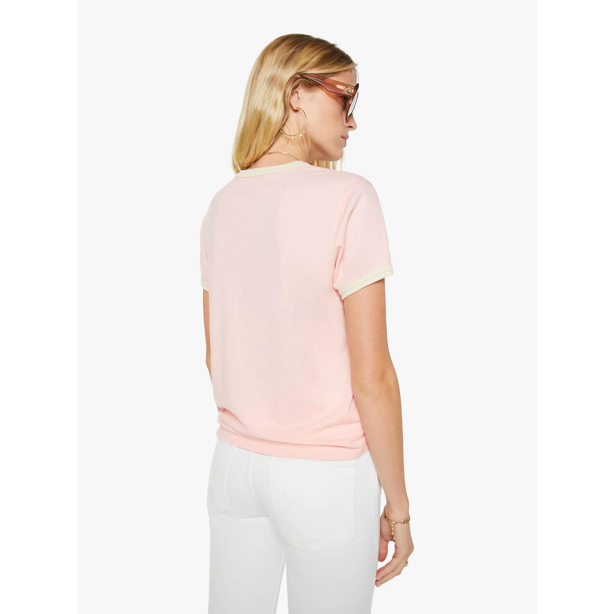 Woman wearing a light pink t-shirt and white pants on a white background