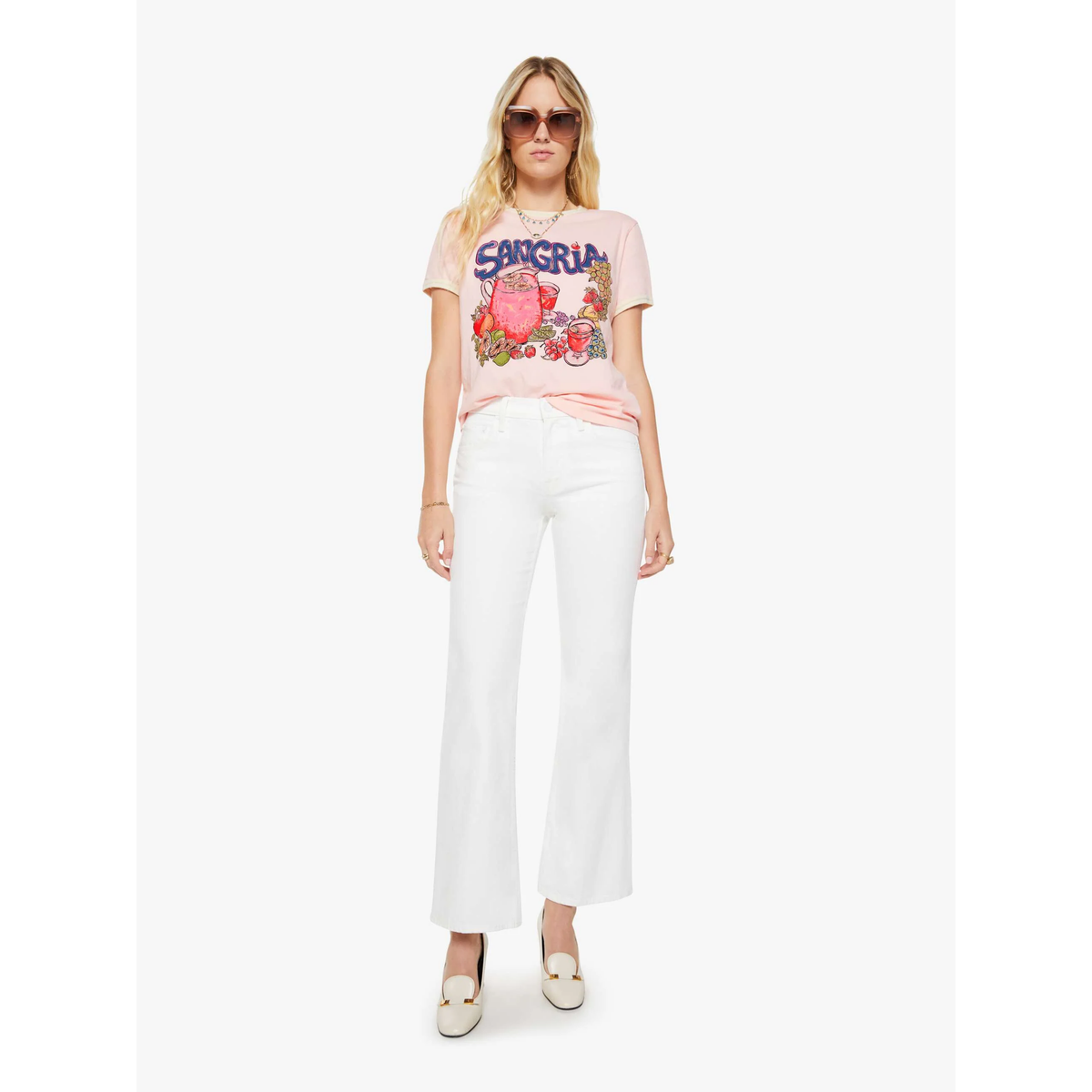 Woman wearing a pink graphic t-shirt and white pants on a white background