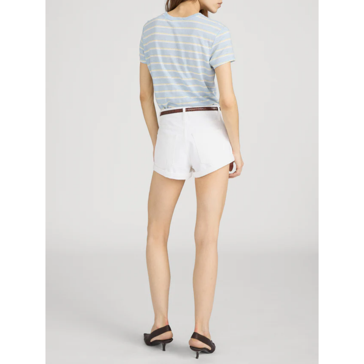 Person wearing a striped shirt and white shorts on a plain background