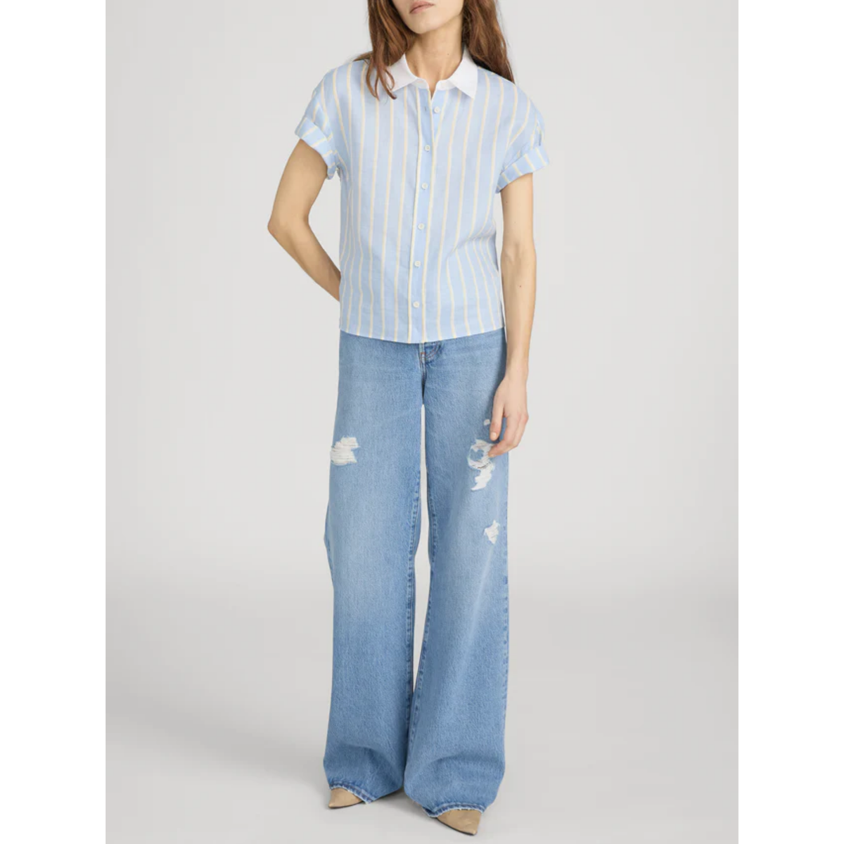 Woman wearing a striped shirt and blue jeans on a white background