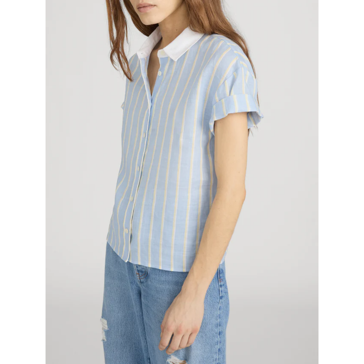 Woman wearing a light blue and white striped shirt with a plain background