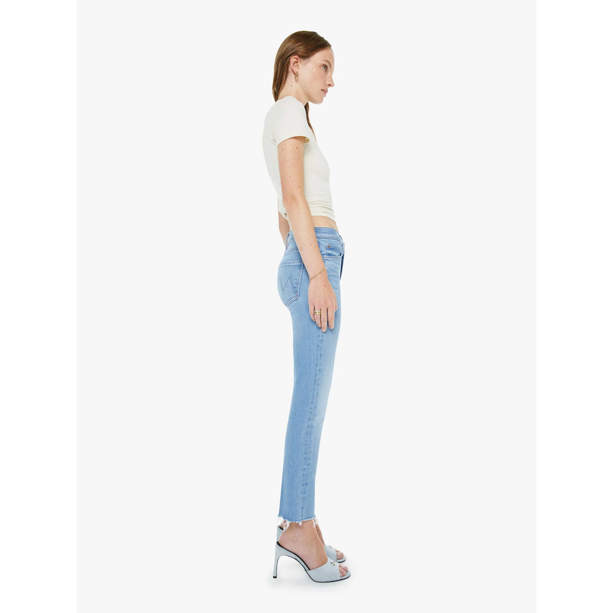 Woman wearing light blue jeans and a white top on a white background