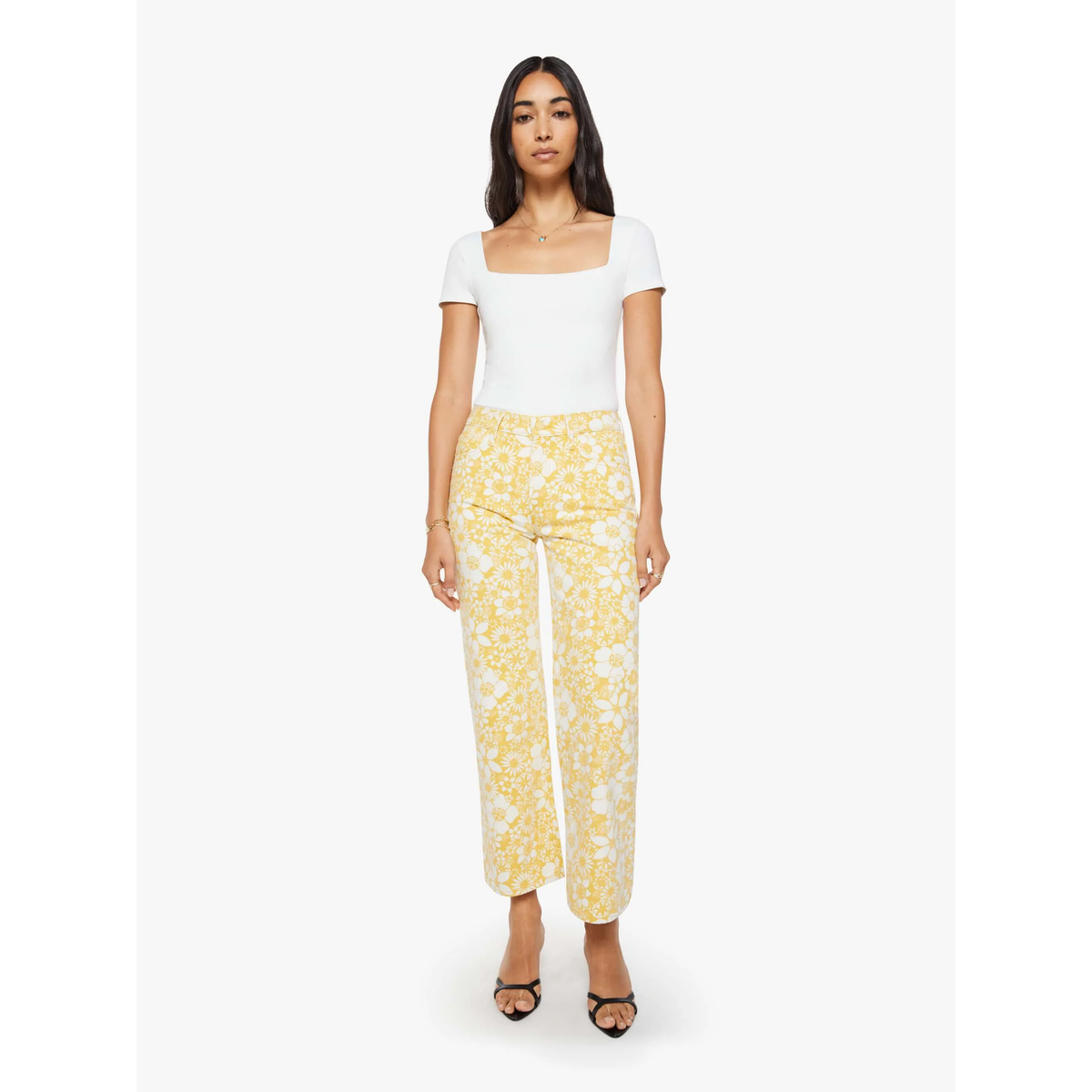 Woman wearing a white top and yellow floral pants on a white background