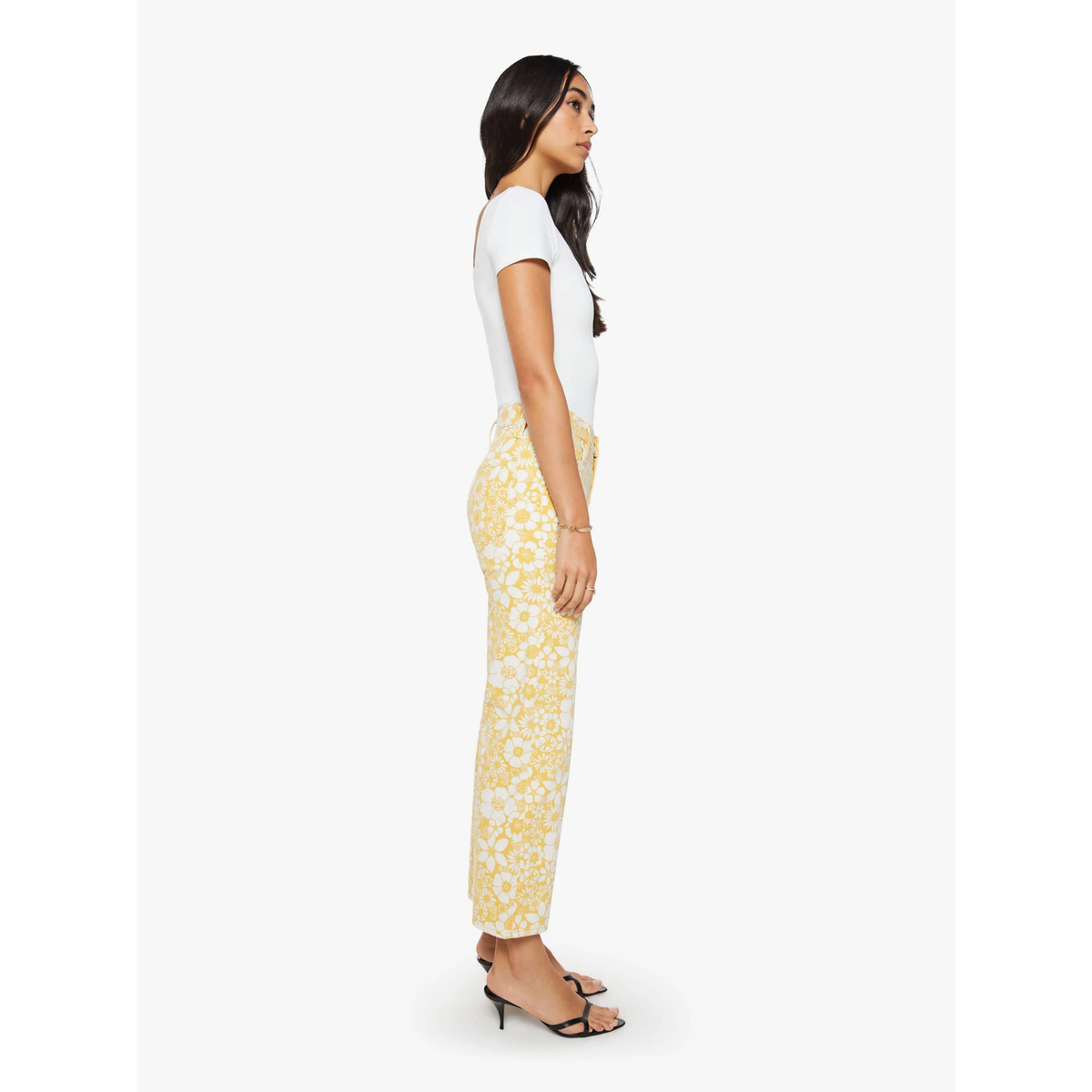 Woman wearing a white top and yellow floral pants on a white background