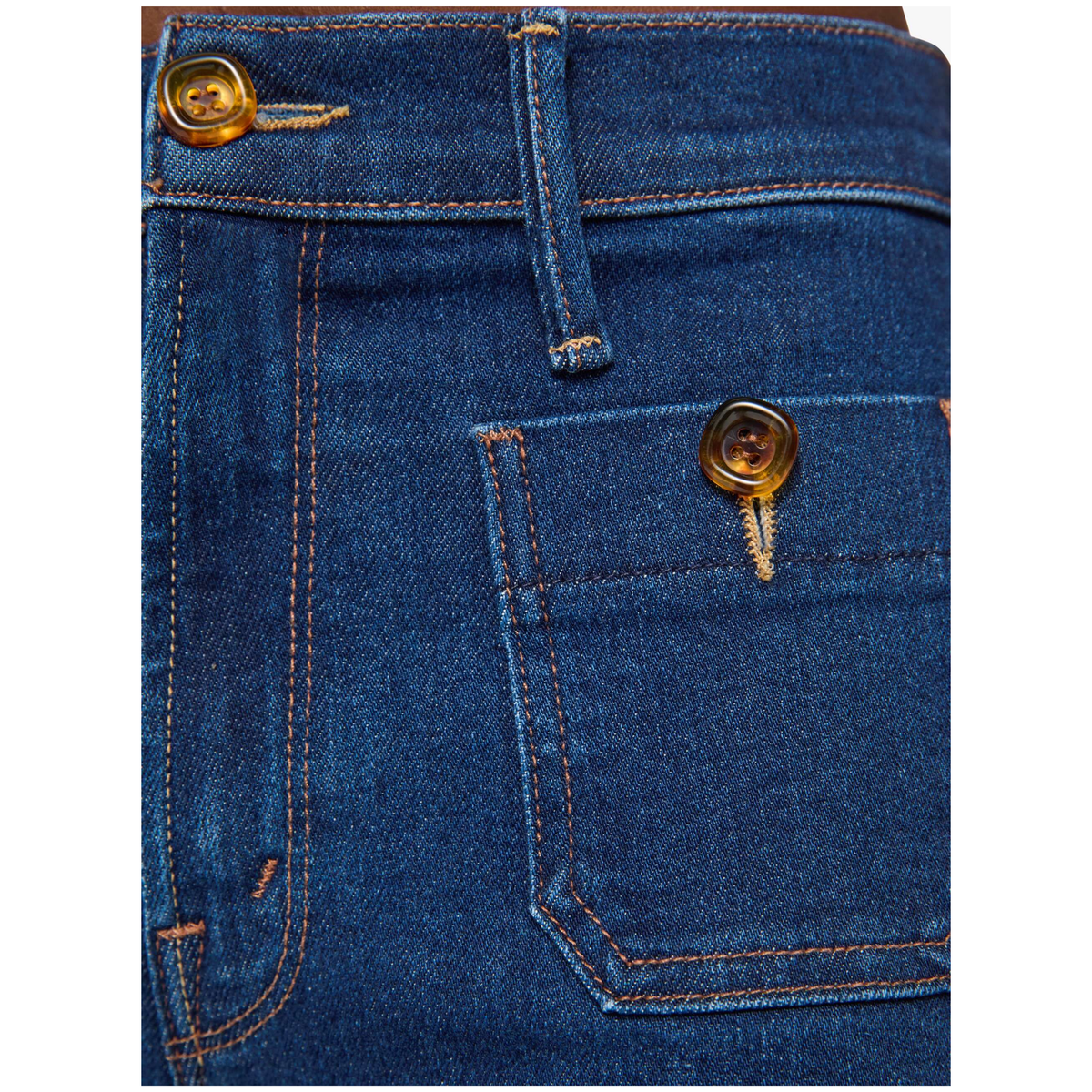 Close-up of dark blue denim jeans showing the back pocket, button, and contrast stitching.
