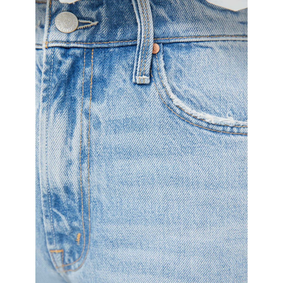 Close-up of a blue denim fabric with stitching details on a white background