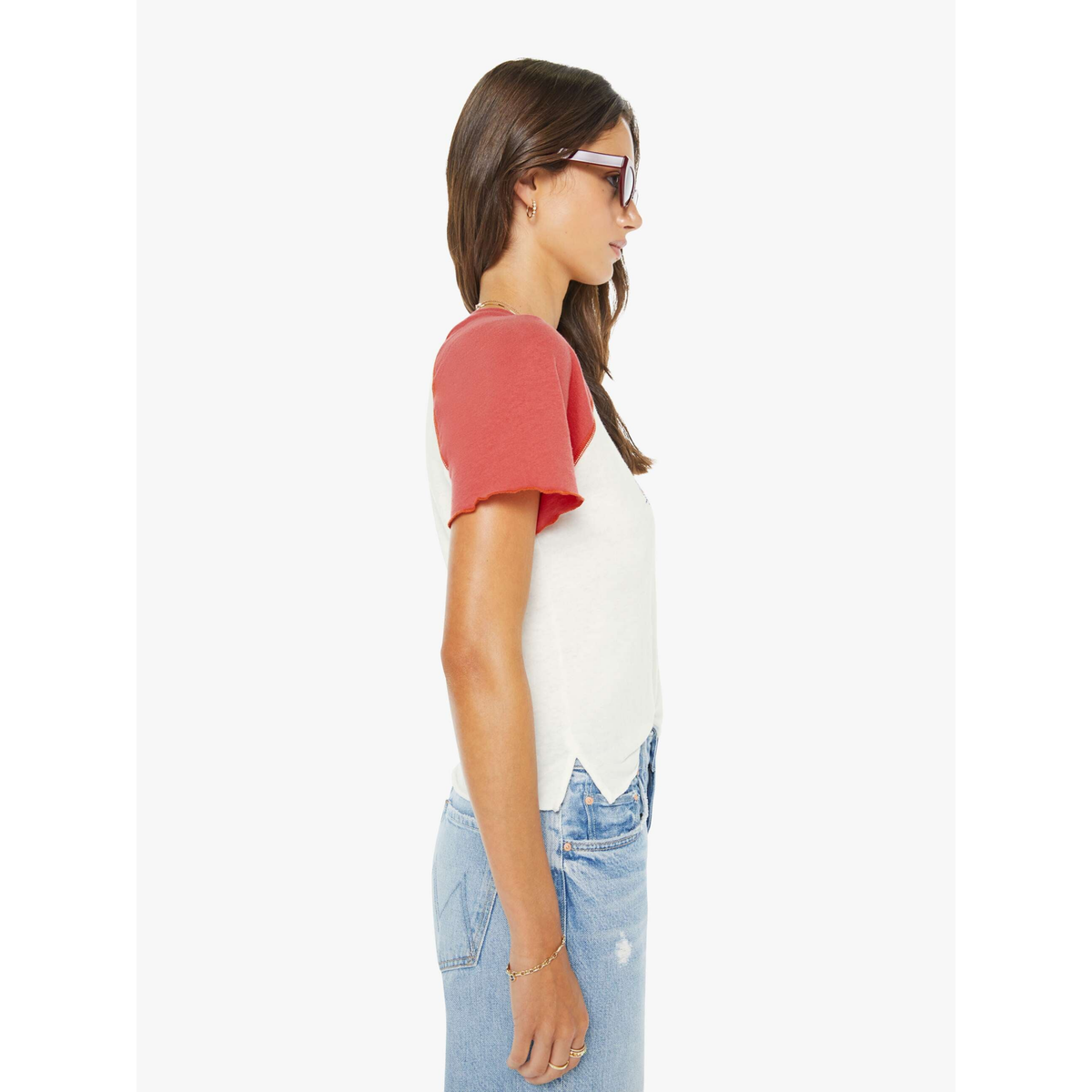 Woman wearing a red and white baseball-style shirt with light blue jeans on a white background