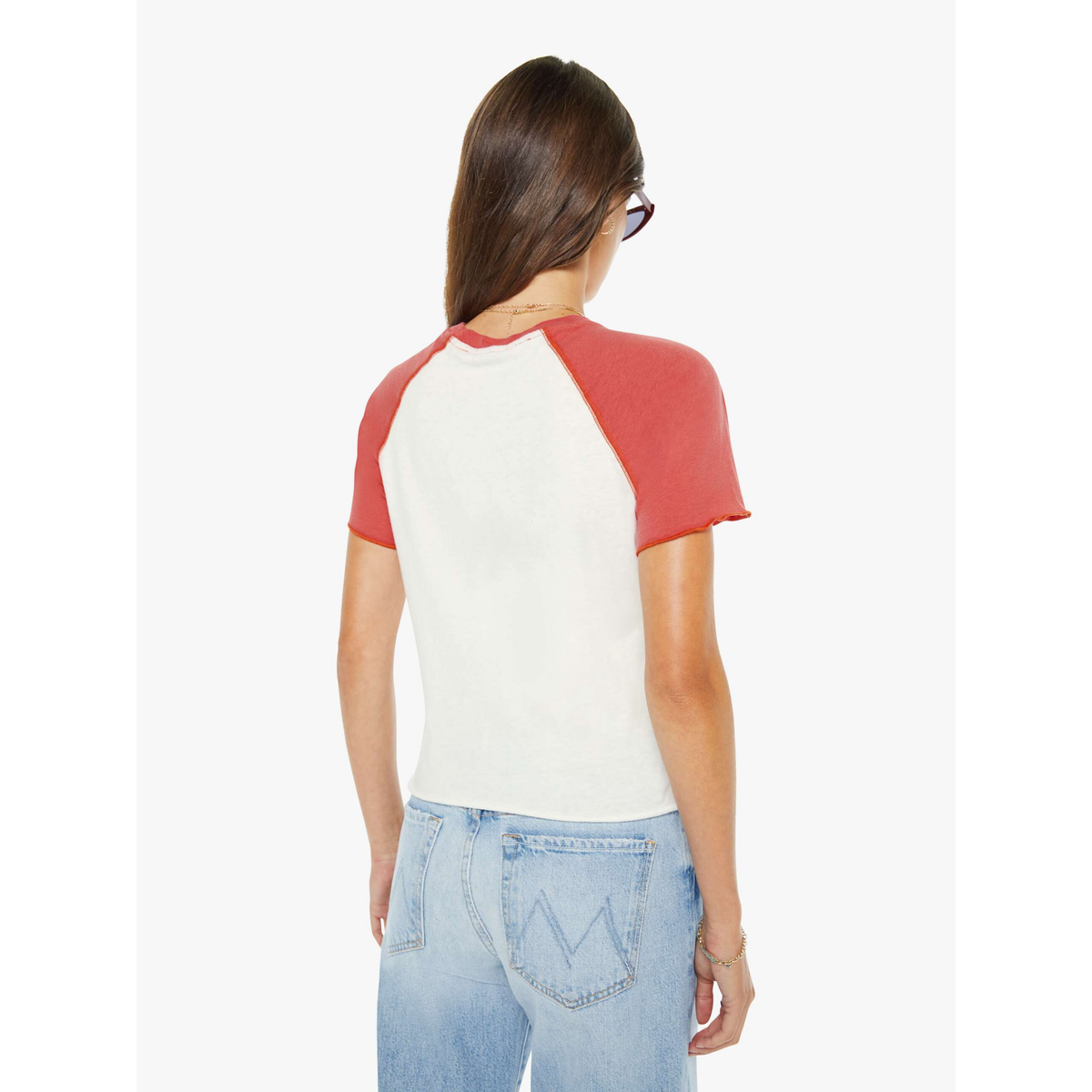 Woman wearing a red and white baseball tee with light blue jeans on a white background