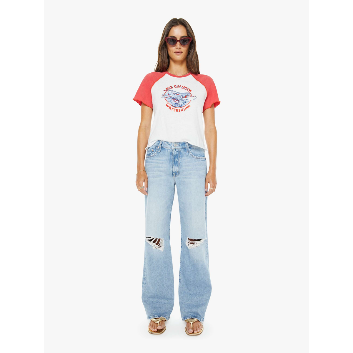 Woman wearing a red and white baseball tee with text and light blue jeans on a white background