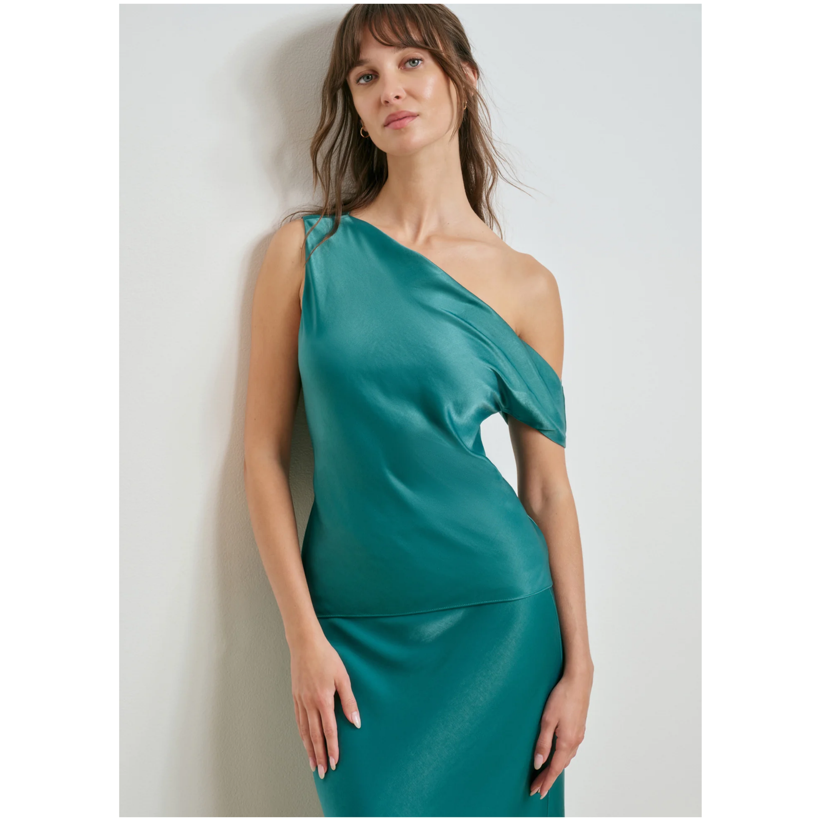 A teal green one-shoulder satin top displayed on a light gray background.