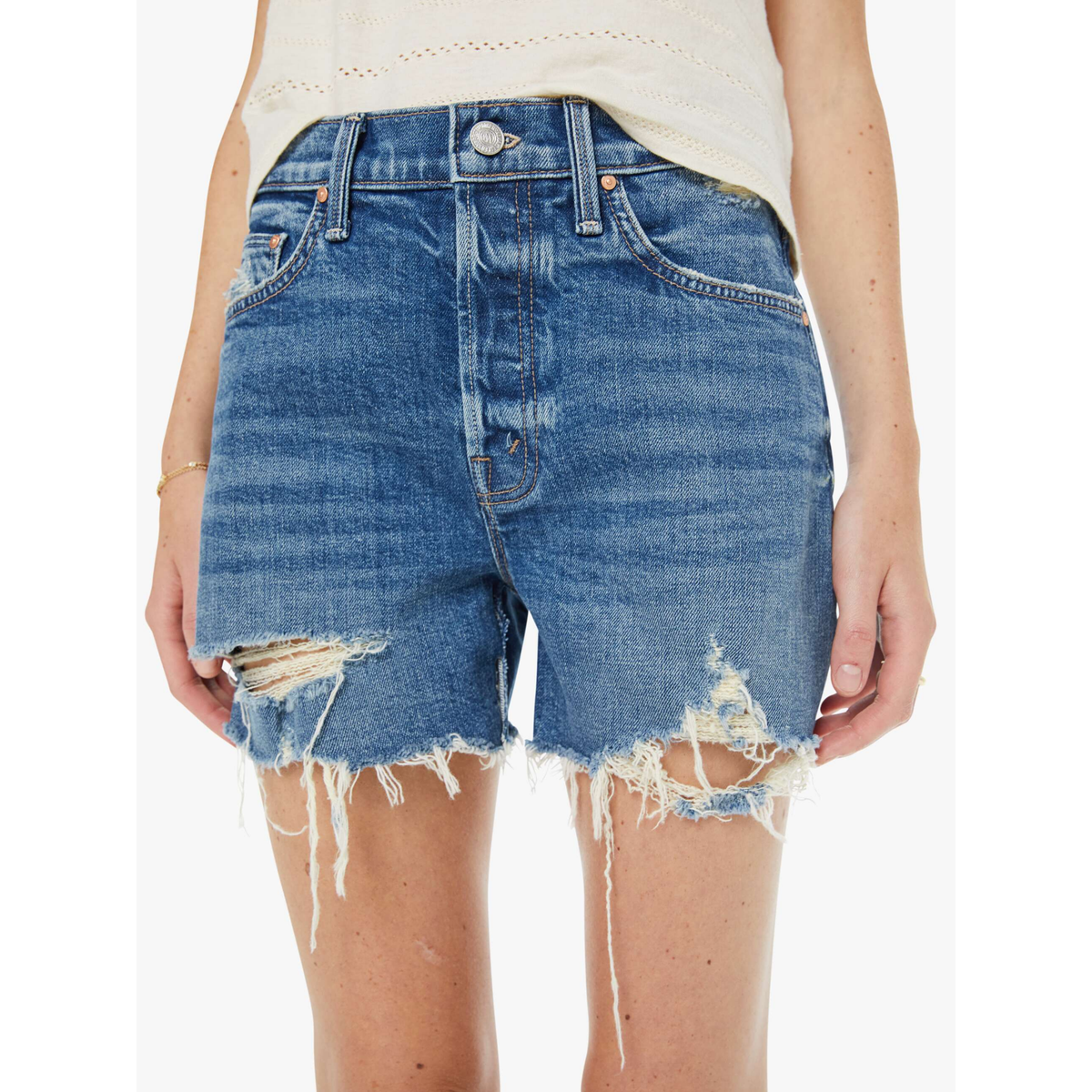 Denim shorts with distressed edges worn by a person on a white background