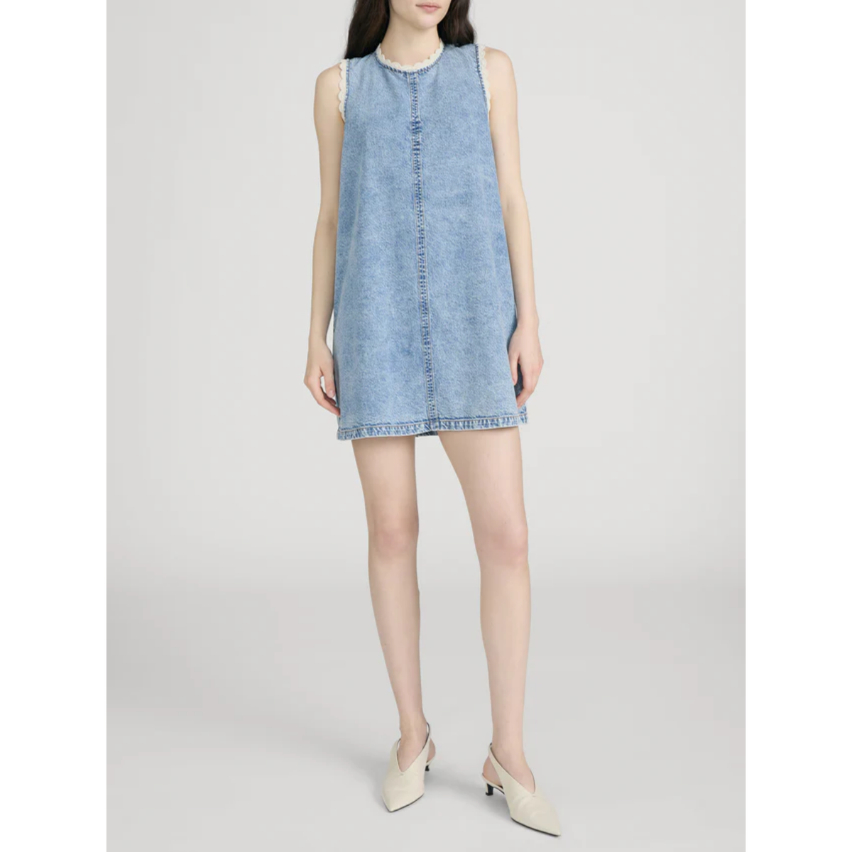 Woman wearing a light blue denim dress on a white background