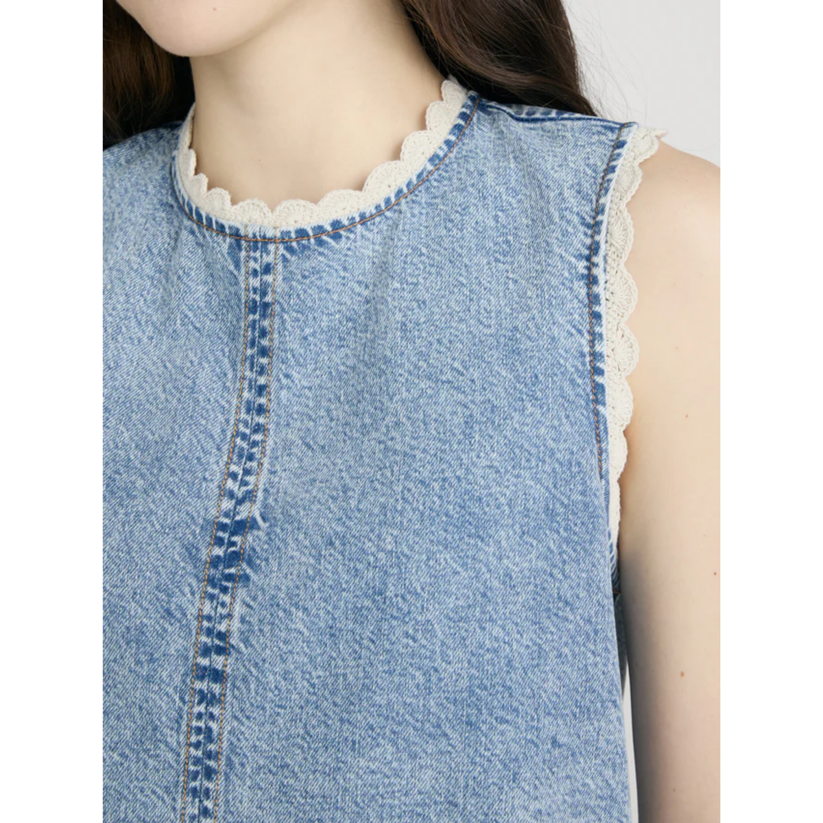 Close-up of a denim sleeveless top with lace trim on a white background
