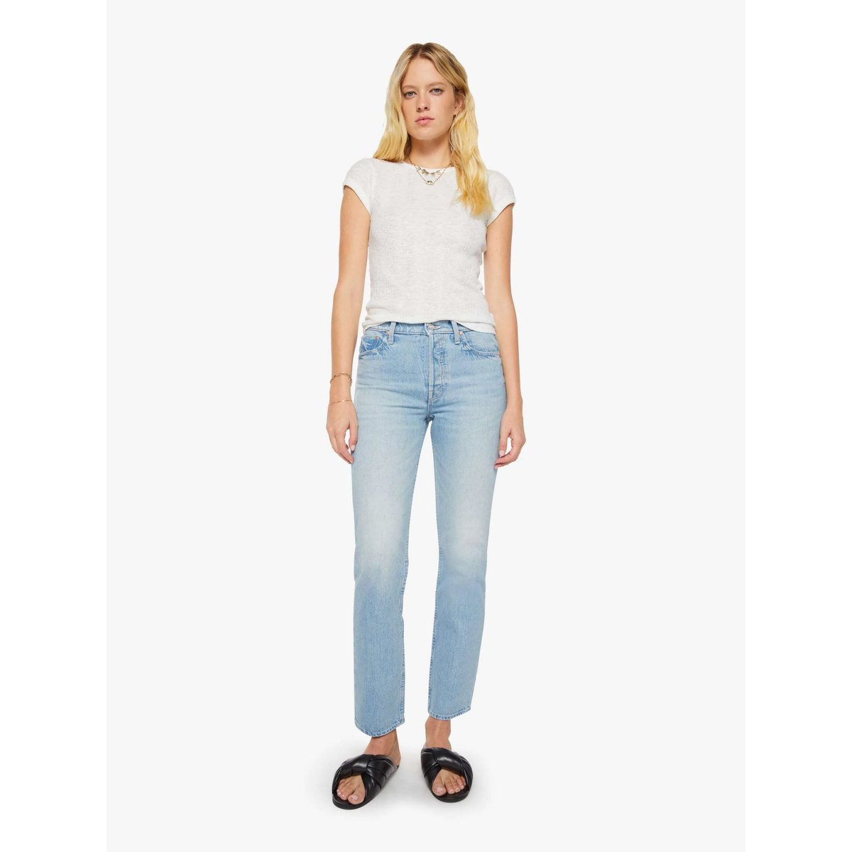 Woman wearing light blue jeans and a white top on a white background