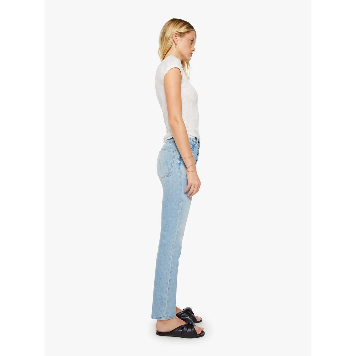 Woman wearing light blue jeans and a white top on a white background