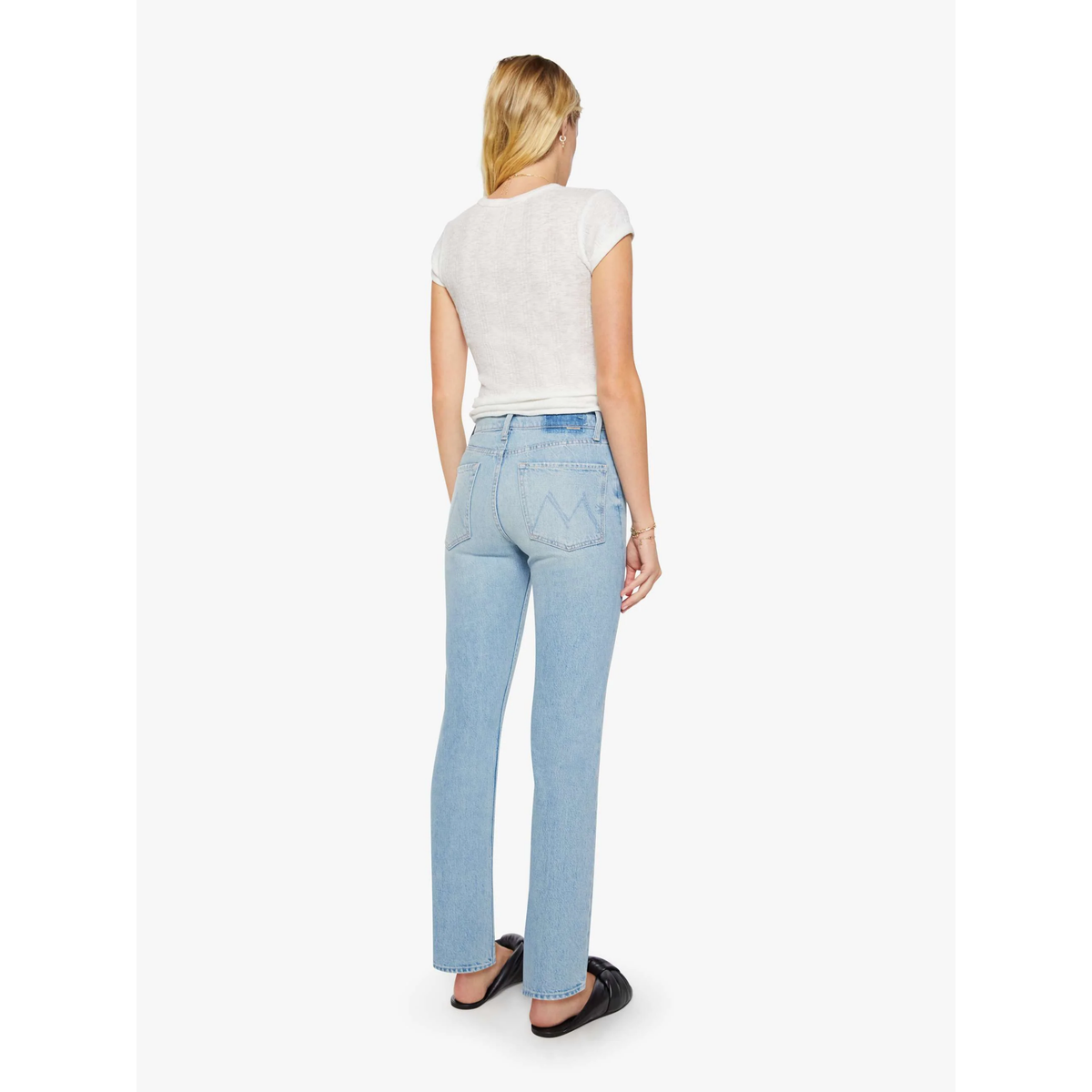 Woman wearing light blue jeans and a white top on a white background