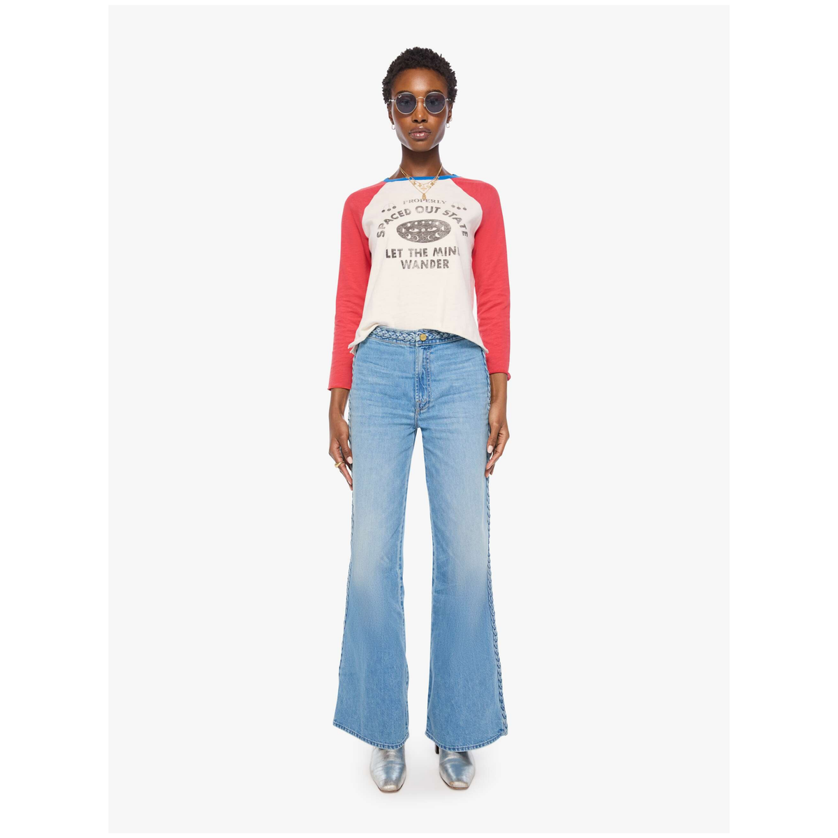 A model wearing a red and white raglan baseball t-shirt with a graphic print, paired with light blue flared jeans and silver sneakers, standing against a plain white background.