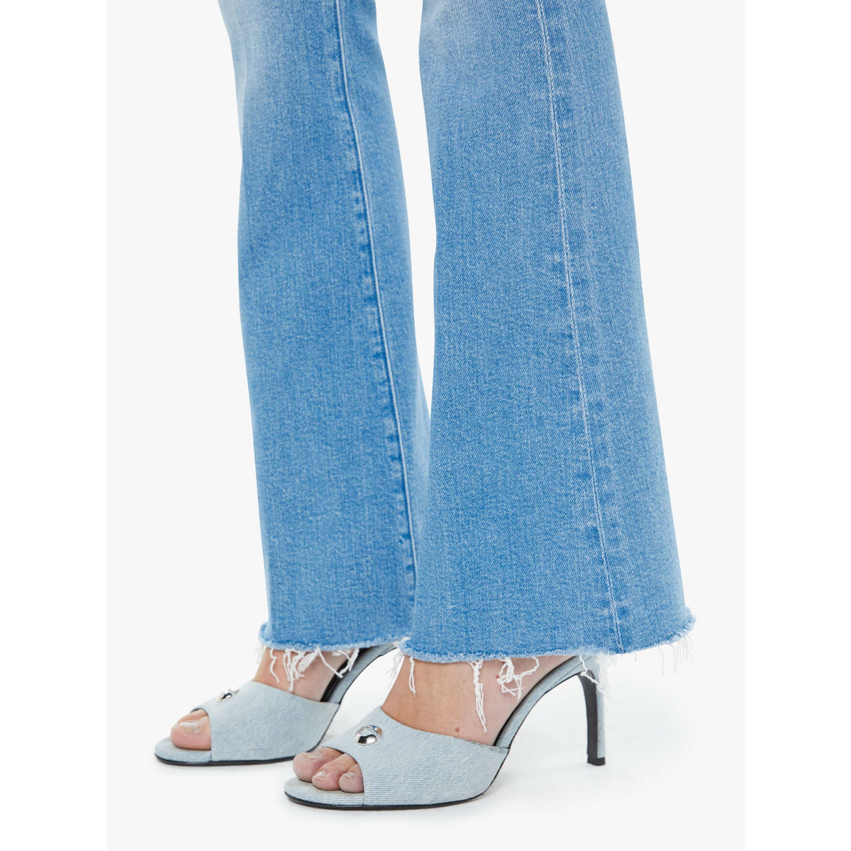 Light blue jeans worn with open-toe high-heeled shoes on a white background