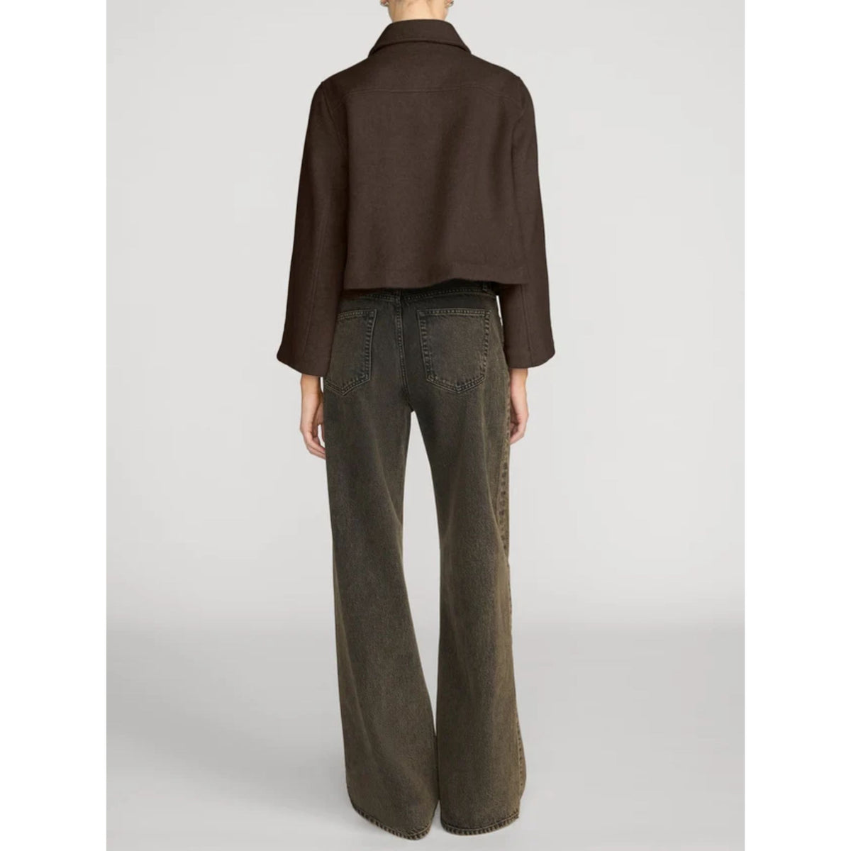 A model shown from the back wearing a dark brown cropped long-sleeve shirt and dark olive green wide-leg jeans, set against a plain light gray studio background.