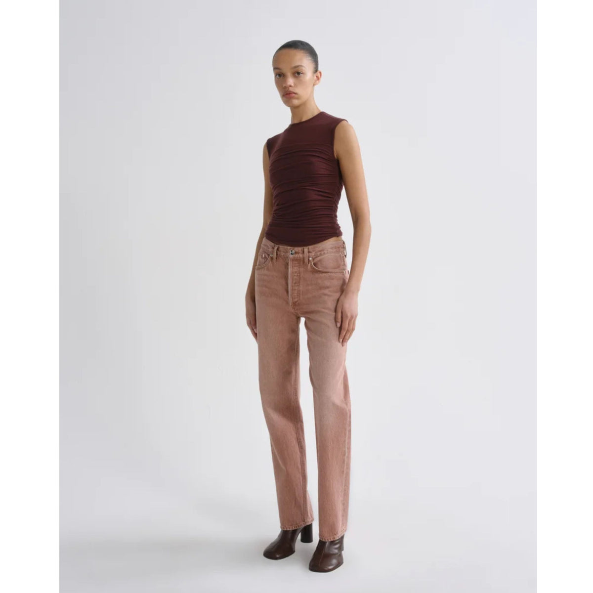Full-length front view of a model wearing the AGOLDE Theodore Tank in Currant, paired with dusty pink pants and black shoes against a light gray background.