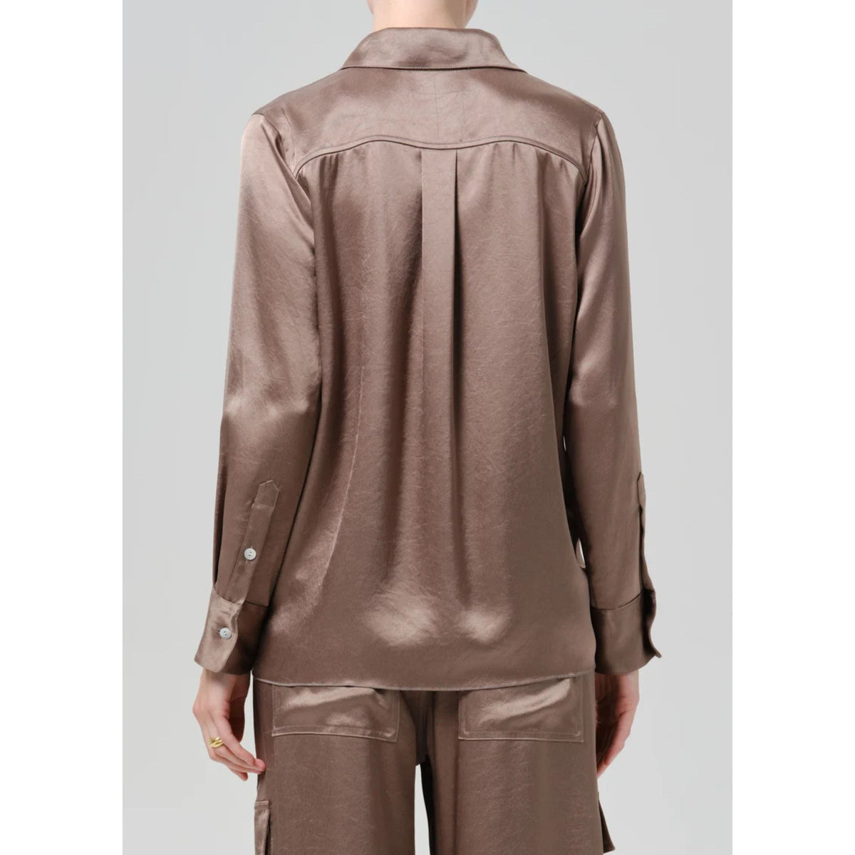 A person shown from the back wearing a shiny taupe-brown satin long-sleeve shirt and matching satin pants against a light gray studio background.