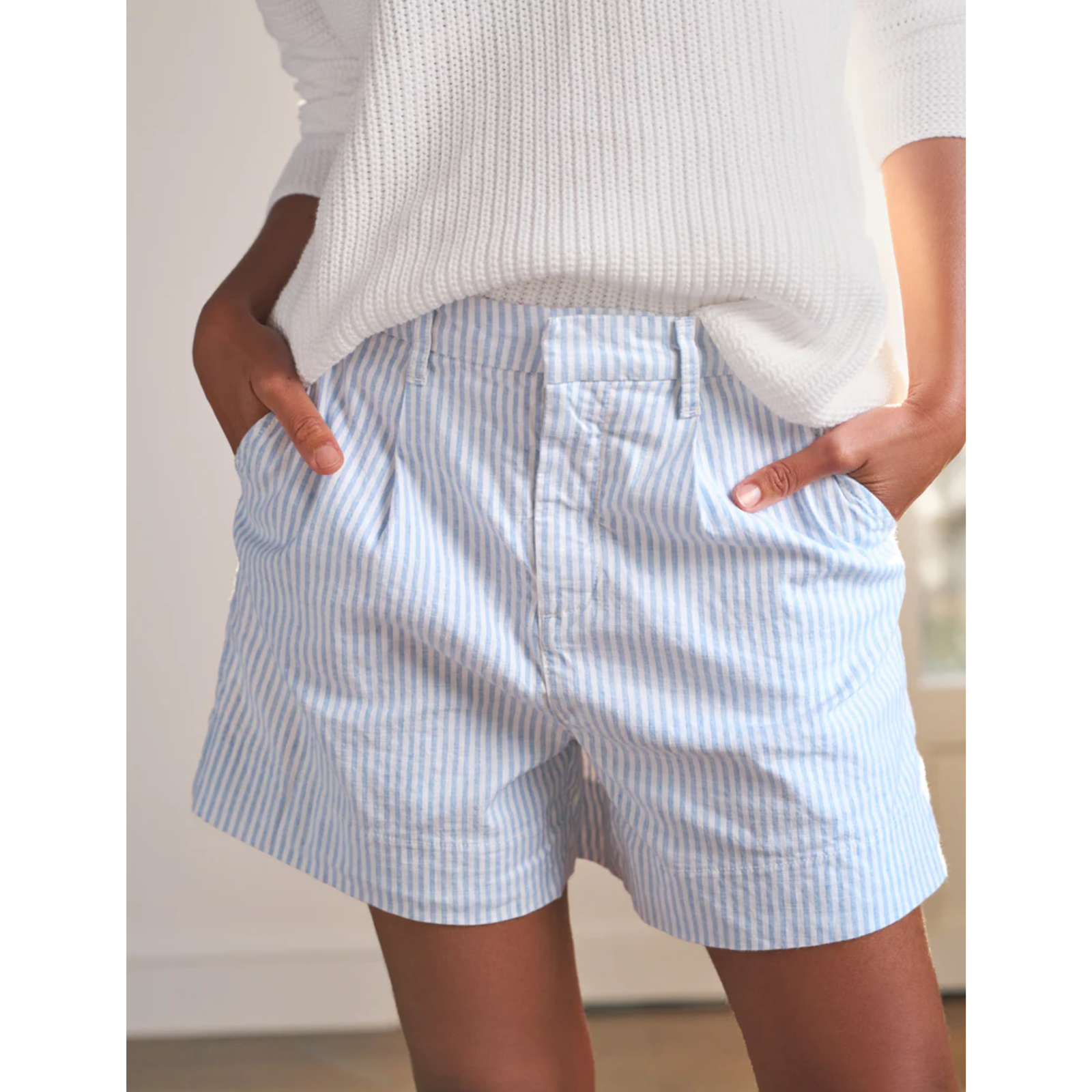 Person wearing light blue striped shorts with a white background