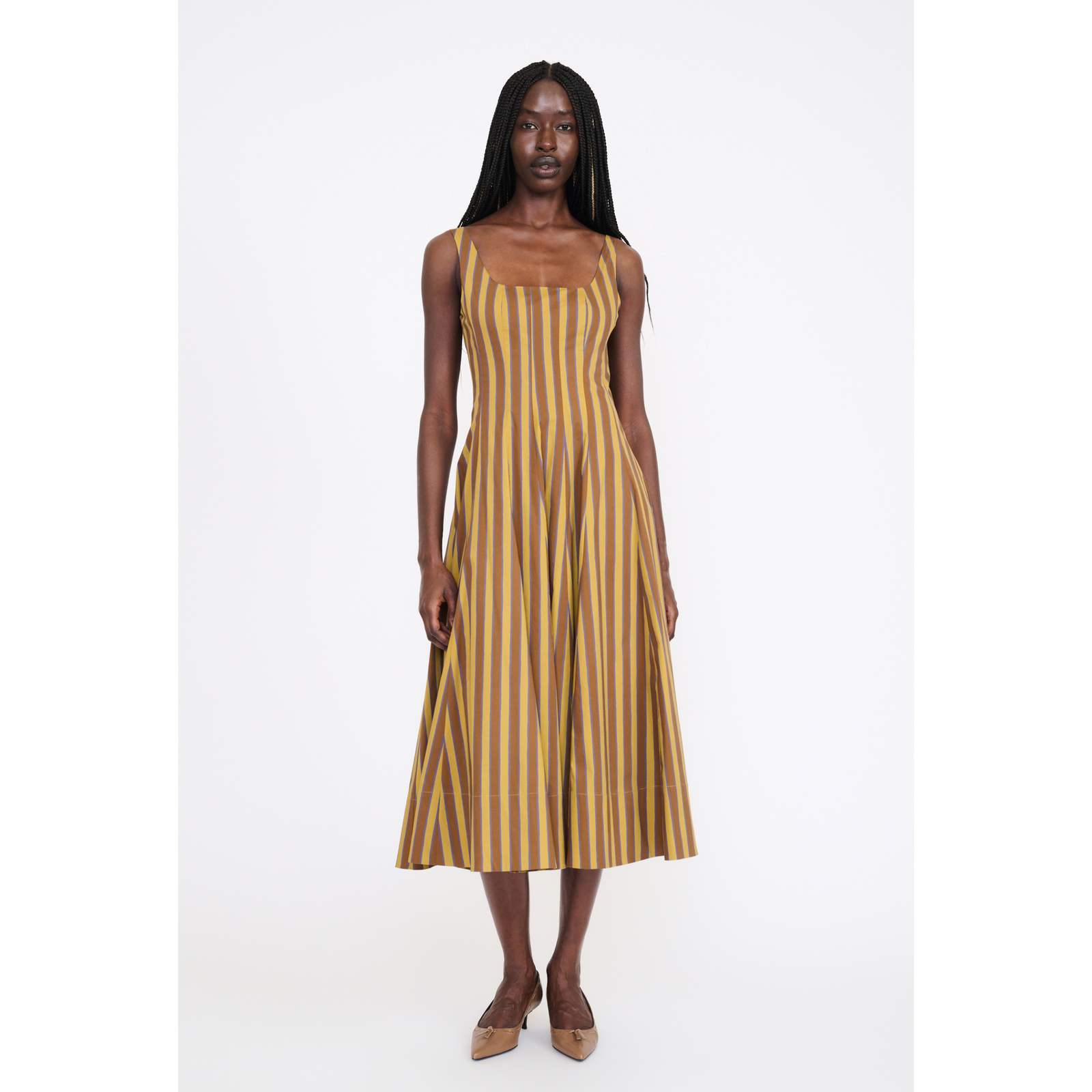A woman modeling a sleeveless midi dress with vertical mustard yellow and brown stripes against a plain white studio background.