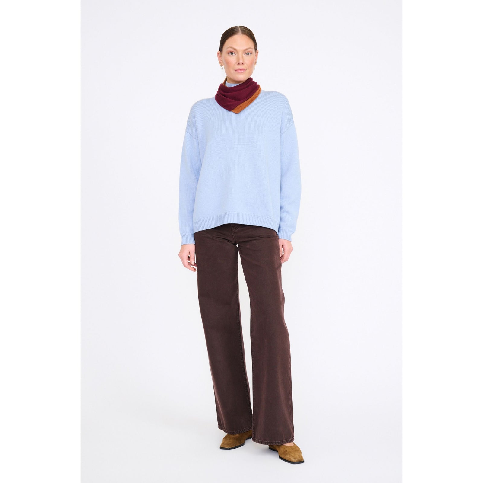 Woman wearing a light blue sweater and brown pants on a white background