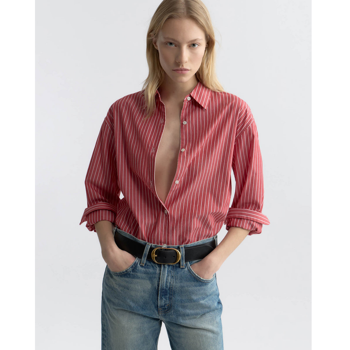Person wearing a red striped shirt and blue jeans on a white background