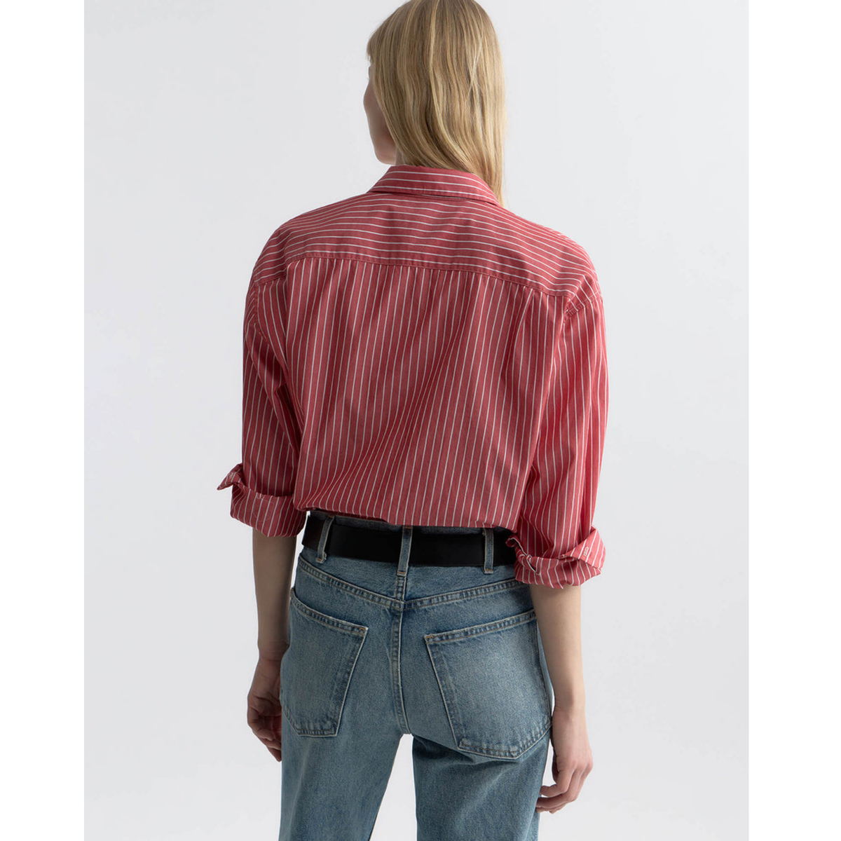 Person wearing a red striped shirt and blue jeans on a white background